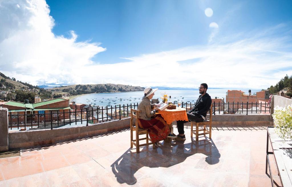 科帕卡巴纳Ima Sumaj Hostel的两人坐在桌子上,享有水景