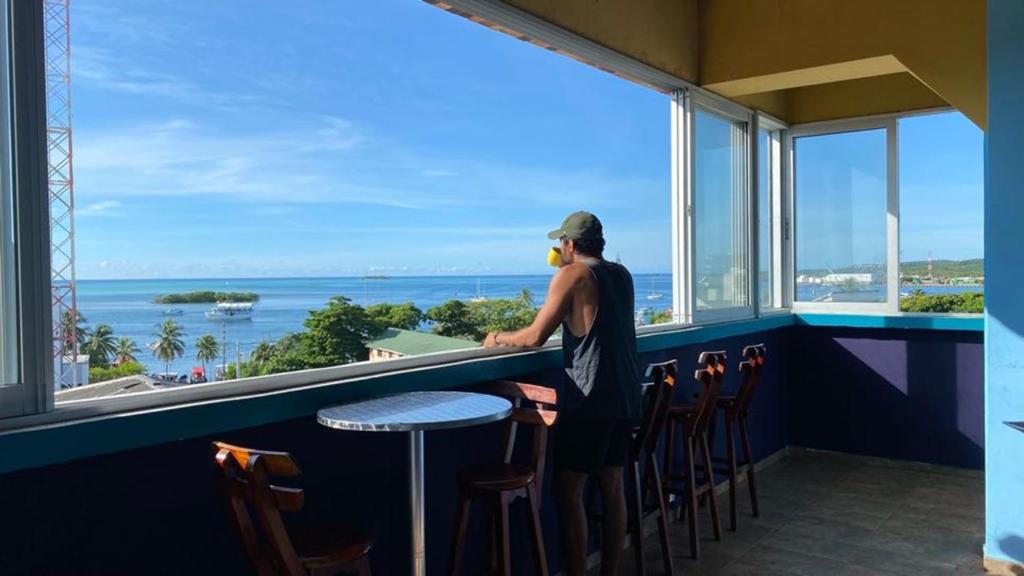 圣安德烈斯Viajero San Andres Hostel的站在酒吧一边眺望海洋的人