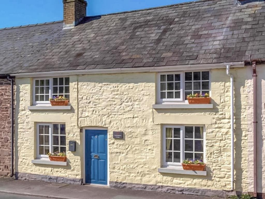 TrecastleCoachingmans Cottage的白色的石头房子,设有蓝色的门窗
