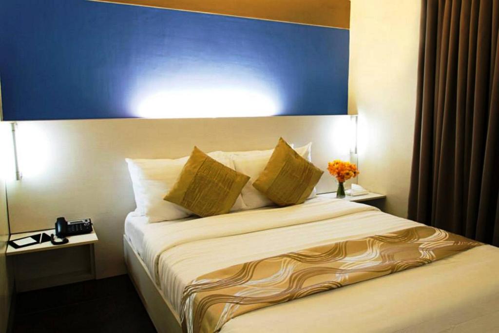 宿务宿务枕头酒店的一间卧室配有一张大床和蓝色床头板