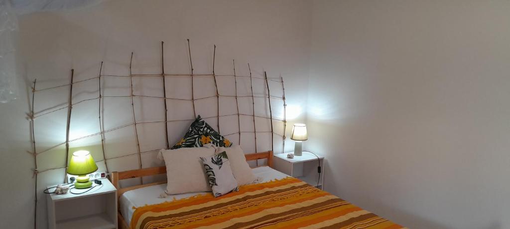 Le Morne RougeO Logis Coco Le Morne-Rouge, Martinique的一间卧室配有一张带两张桌子和两盏灯的床。