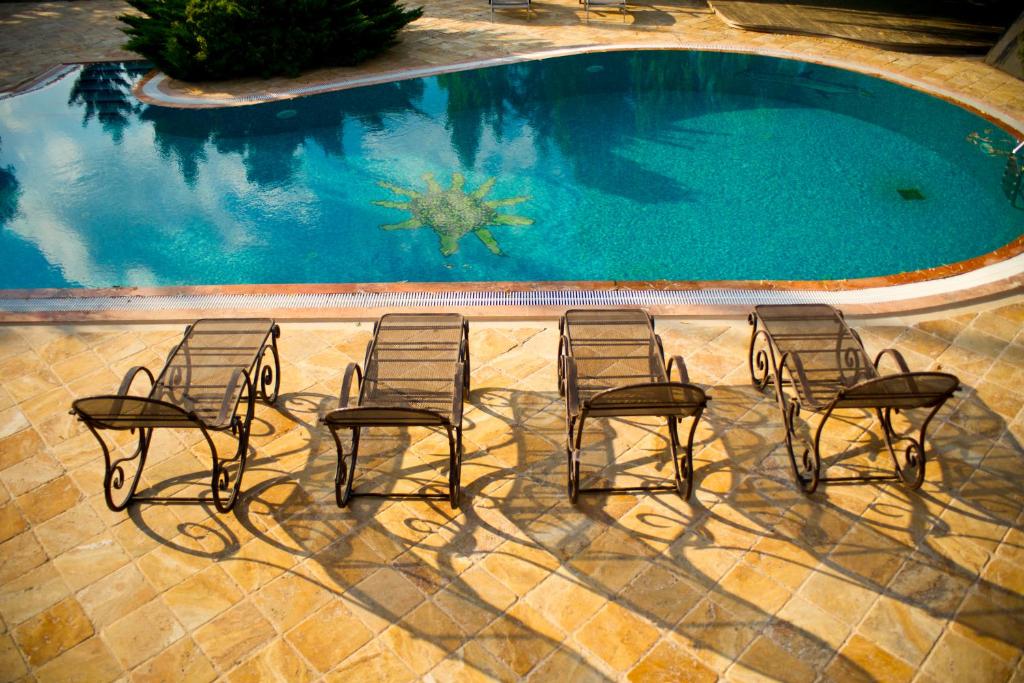 斋沙默尔Desert Residency camp Jaisalmer with swimming pool的一组椅子坐在游泳池旁