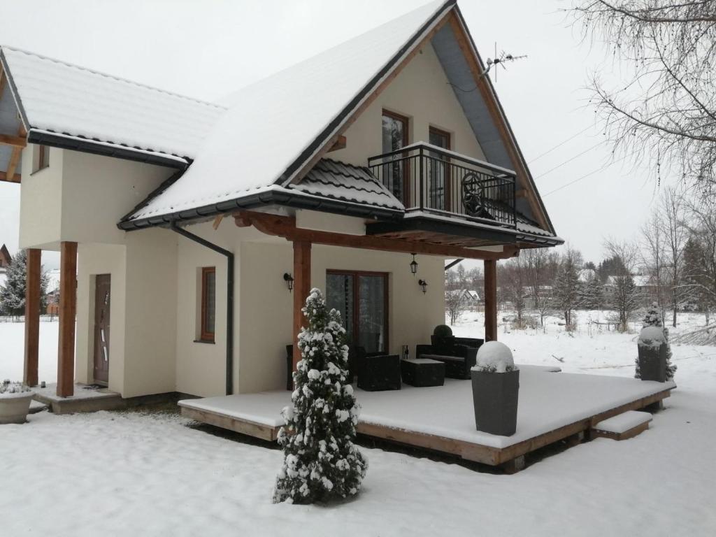 斯扎法拉瑞Domek w Zaciszu的院子里的雪覆盖着圣诞树的房子