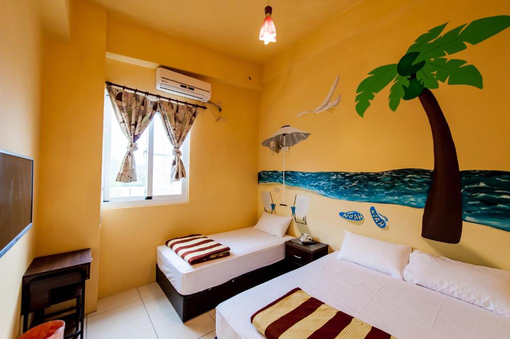 绿岛诺亚民宿的卧室配有两张床,墙上挂着一棵棕榈树