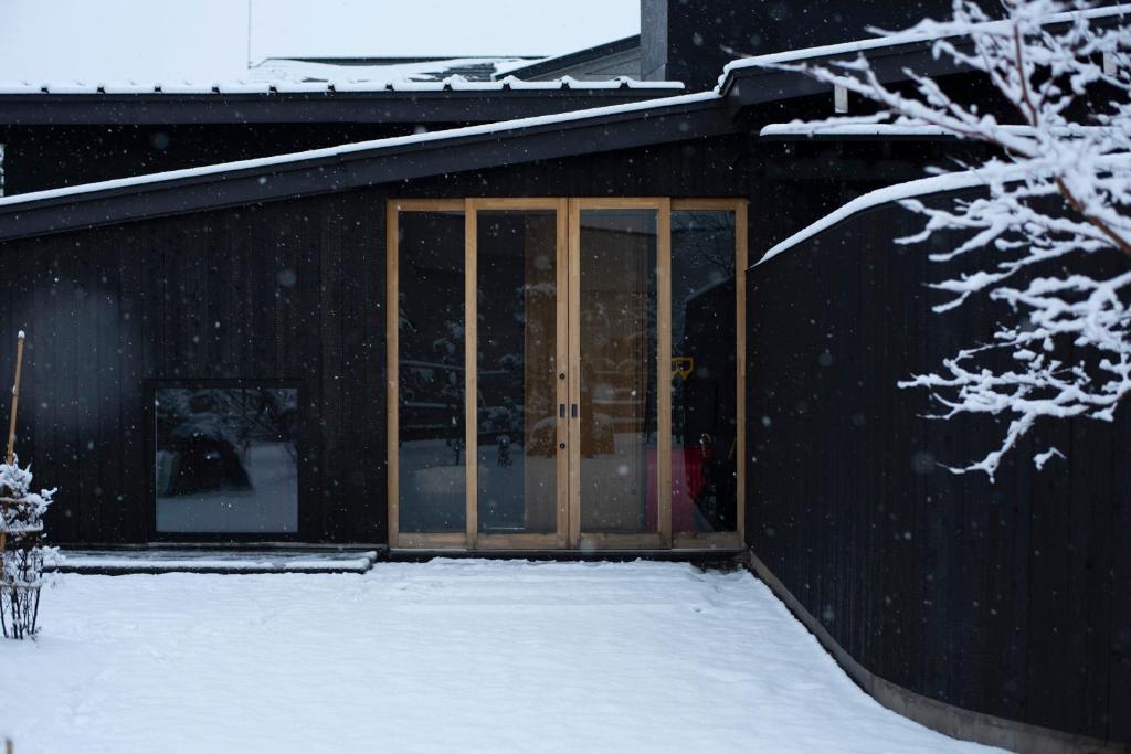 Goshogawaraこもる五所川原的雪中带玻璃门的黑色建筑