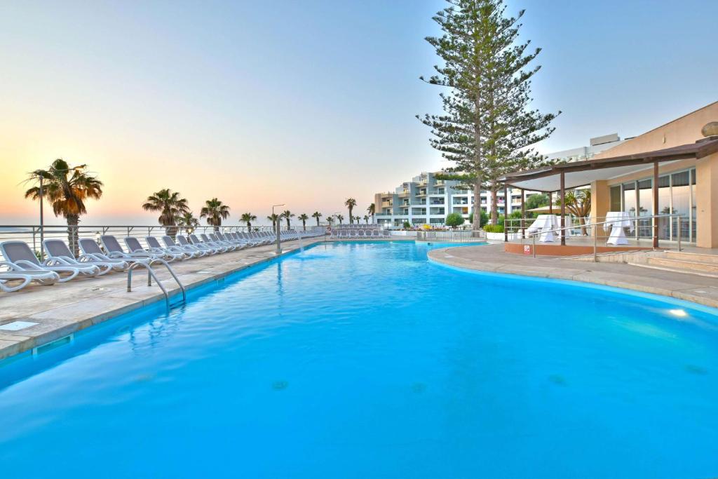 圣保罗湾城DoubleTree by Hilton Malta的一个带椅子的大型游泳池,一个度假村