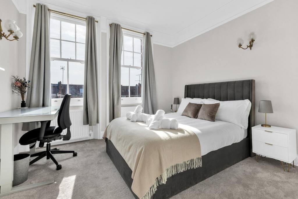 伦敦Luxury 3 bedroom apartment in the heart of High Street Kensington, London.的白色卧室设有床、书桌和窗户