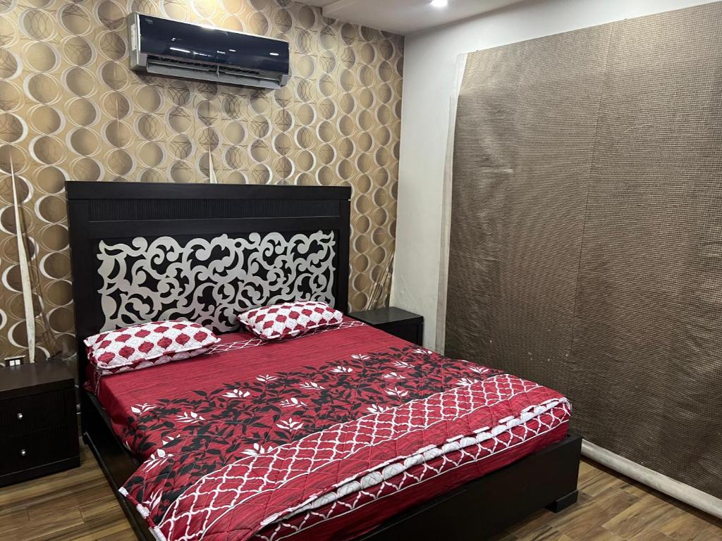 GujrānwālaPrime Plaza的一间卧室配有红色的床和红色和白色枕头