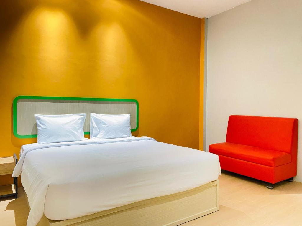 SukaramiRuma Ruma Hotel Kenten - Palembang的一间卧室配有一张床和一张红色椅子