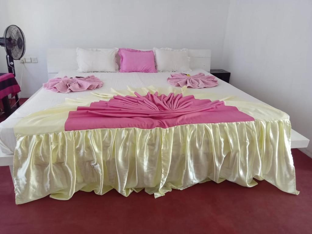 波隆纳鲁沃New Gama Guest的一张大床,配有粉红色和黄色的床单和粉红色的枕头