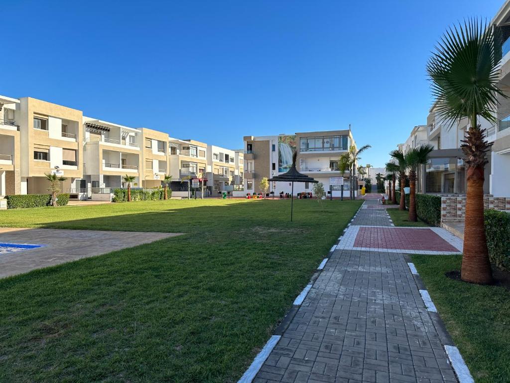 曼苏里亚Bel appartement à Malaga Beach El Mansouria的棕榈树公园和建筑中的步行道