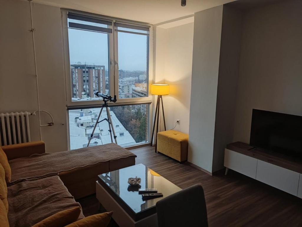 斯科普里Sky view luxury Center Skopje apartments的客厅,窗户前的三脚架上配有摄像头