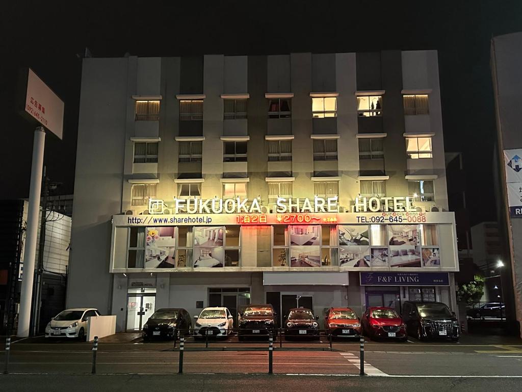 福冈Fukuoka Share Hotel的一座建筑,晚上停在前面