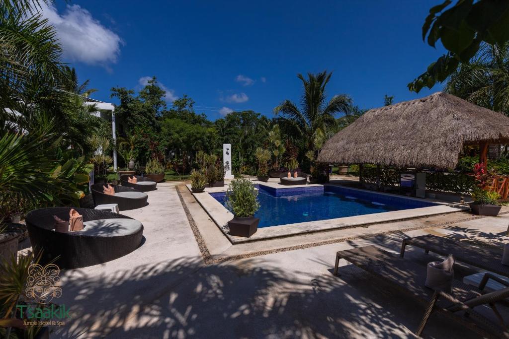 坎昆Tsaakik Jungle Hotel & Spa的一个带游泳池和草伞的度假胜地