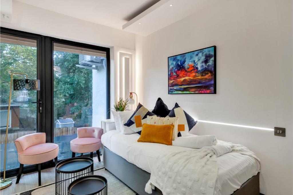 伦敦Cosy Studio in Great Location!的一间卧室配有大床和粉红色的椅子