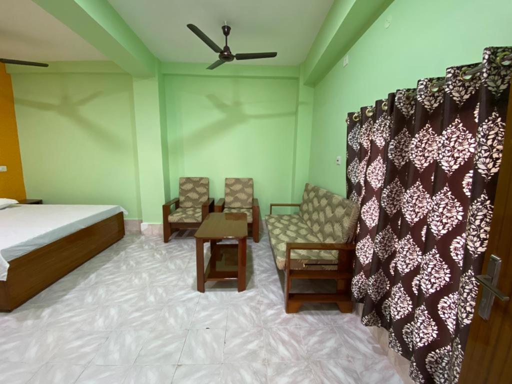 古瓦哈提HOTEL RITZ的一间卧室配有一张床和椅子以及吊扇