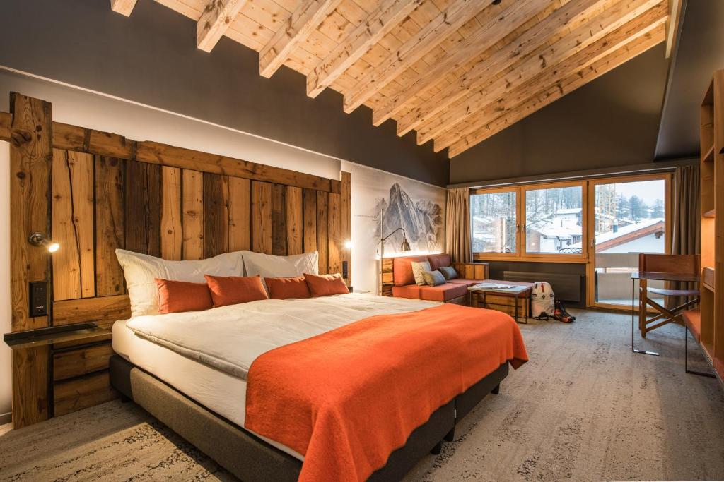 采尔马特贝斯坎普酒店的一间卧室配有一张带橙色毯子的大床