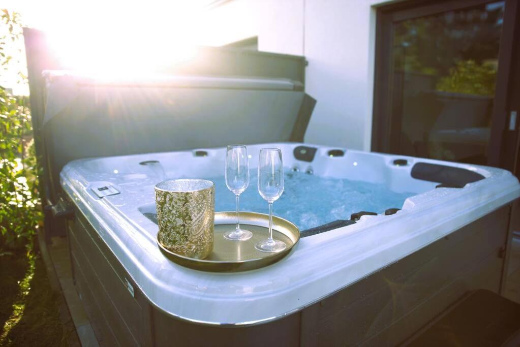 SandweilerBeautiful 4BR House with Jacuzzi的热水浴池,配有2个玻璃杯和酒杯托盘