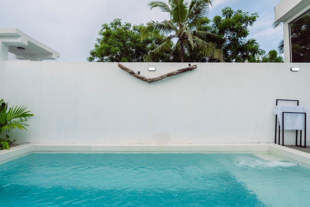 瓦塔穆Trio Villas Watamu的白色墙壁前的游泳池