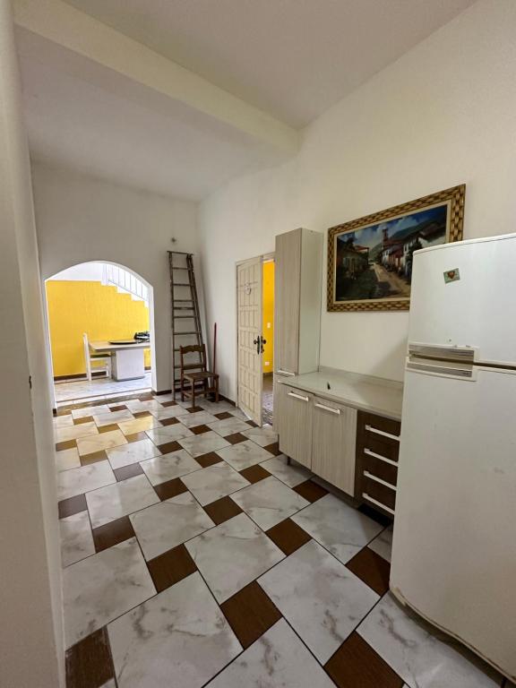 蒙加瓜Hostel Encanto de Mongaguá的厨房配有冰箱,地面铺有瓷砖地板。