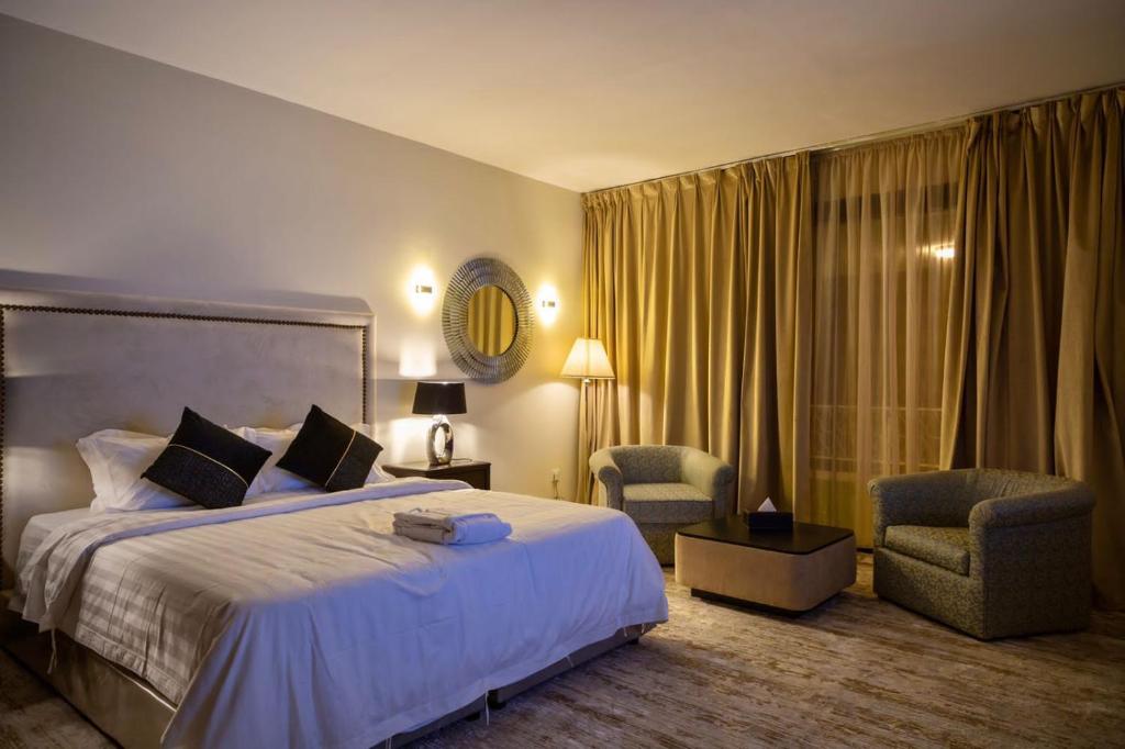 巴勒如拉斯Ghodran Hotel and Resort的酒店客房带一张大床和两张椅子