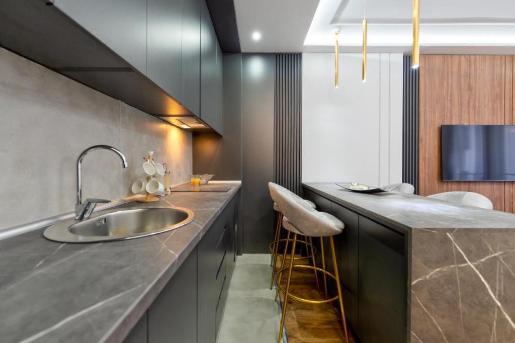 兹拉蒂博尔Mans lux 8 Apartman的厨房配有水槽和带椅子的柜台。