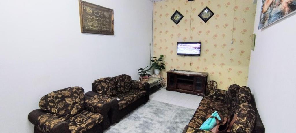 Kampung GurunHomestay D'Murni的客厅配有两张沙发和一台电视机