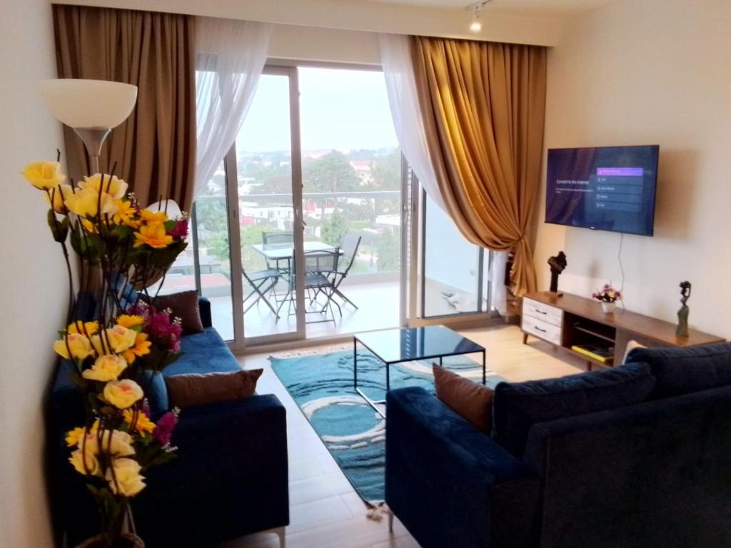 阿克拉1 BDR 74SQM Luxury APT with separate Bedroom Pool, Gym, Balcony, King Size Bed Cantonments的客厅配有蓝色的沙发和玻璃桌