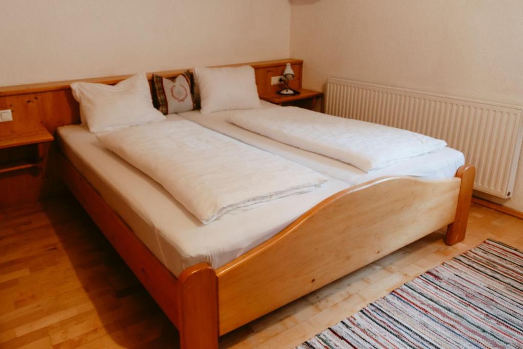 巴特霍夫加施泰因Tofererhof的一张带白色床单和枕头的木床