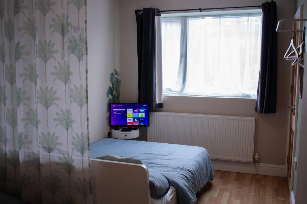 伦敦Cosy apartment 7 mins walk from Wembley stadium的一间卧室配有一张床,电视