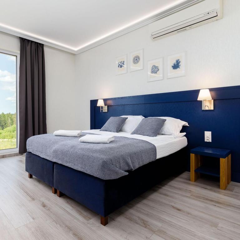 奥尔什丁Nowoczesne apartamenty Jezioro Ukiel Zatoka Miła Plaża Miejska的蓝色和白色的卧室设有一张大床