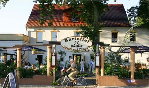 吕本瑙卡托非加斯特豪斯尼德宾希酒店的坐在餐厅前骑车的人