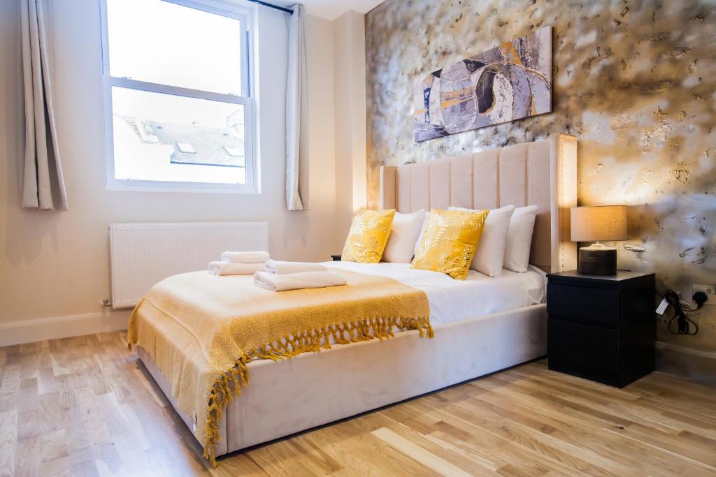 伦敦Luxury Fulham 3 bedroom Garden House的一间卧室配有一张带黄色枕头的床和一扇窗户