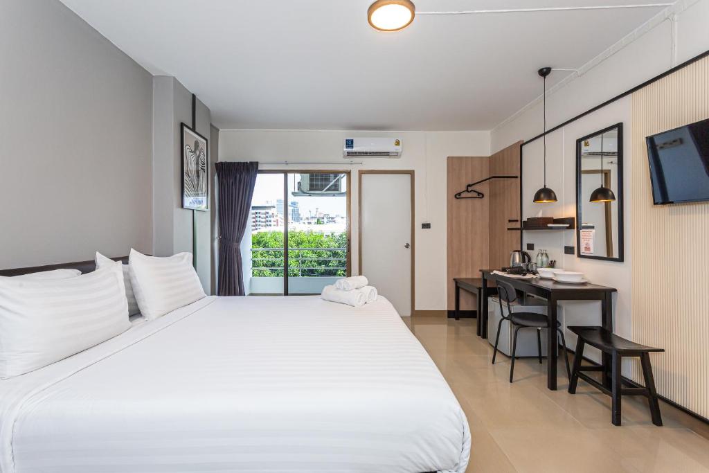 曼谷CK2 Hotel SHA EXTRA PLUS的卧室配有一张白色大床和一张书桌