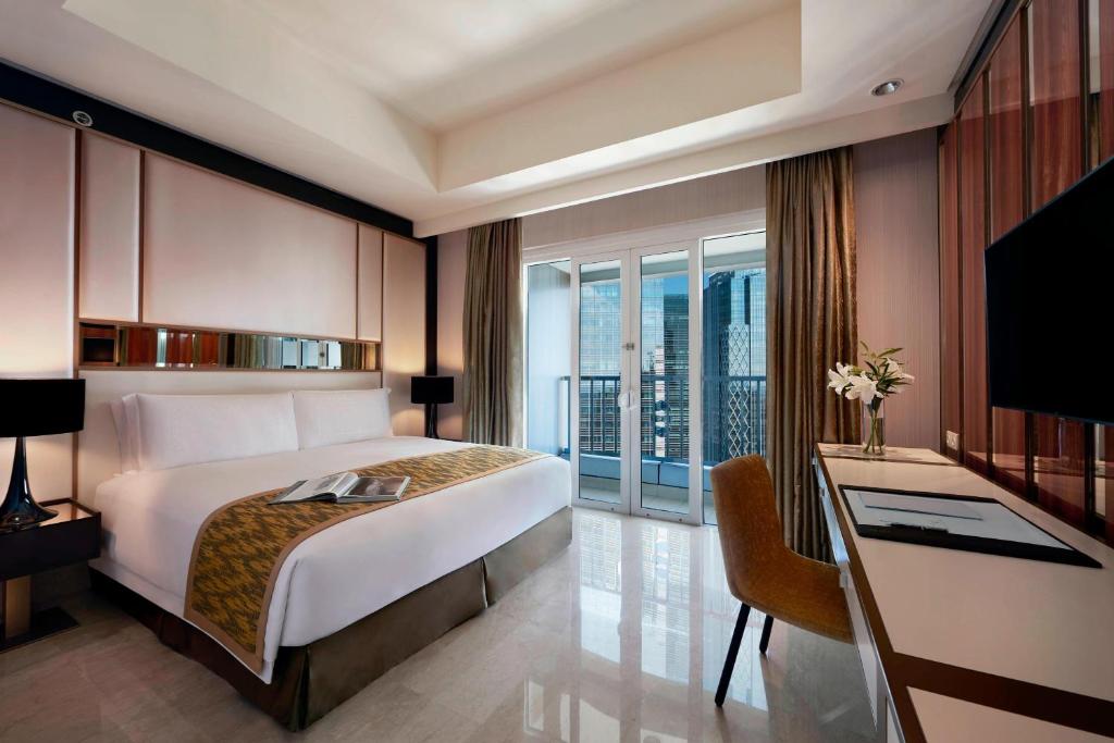 雅加达丽思卡尔顿酒店雅加达太古广场公寓的一间卧室配有一张床、一张书桌和一个窗户。
