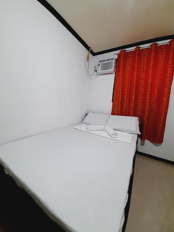 BurgosSubangan Room 6的红色窗帘的房间的一张床位