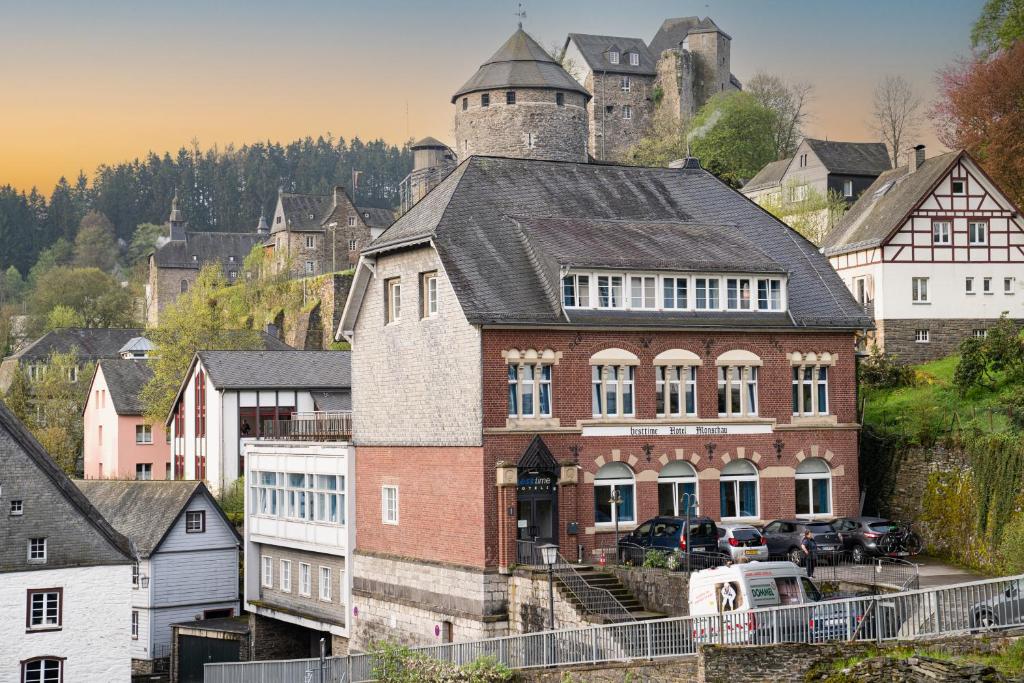 蒙绍besttime Hotel Monschau的一座大砖砌建筑,后面是一座城堡