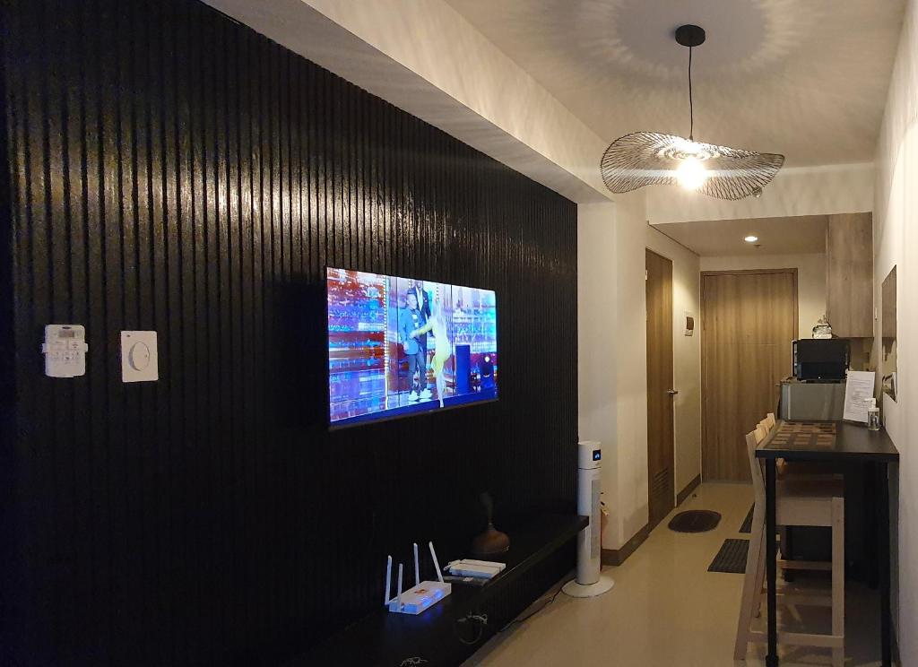 马尼拉C Place - Capsule A的一间客厅,在黑色的墙上配有电视