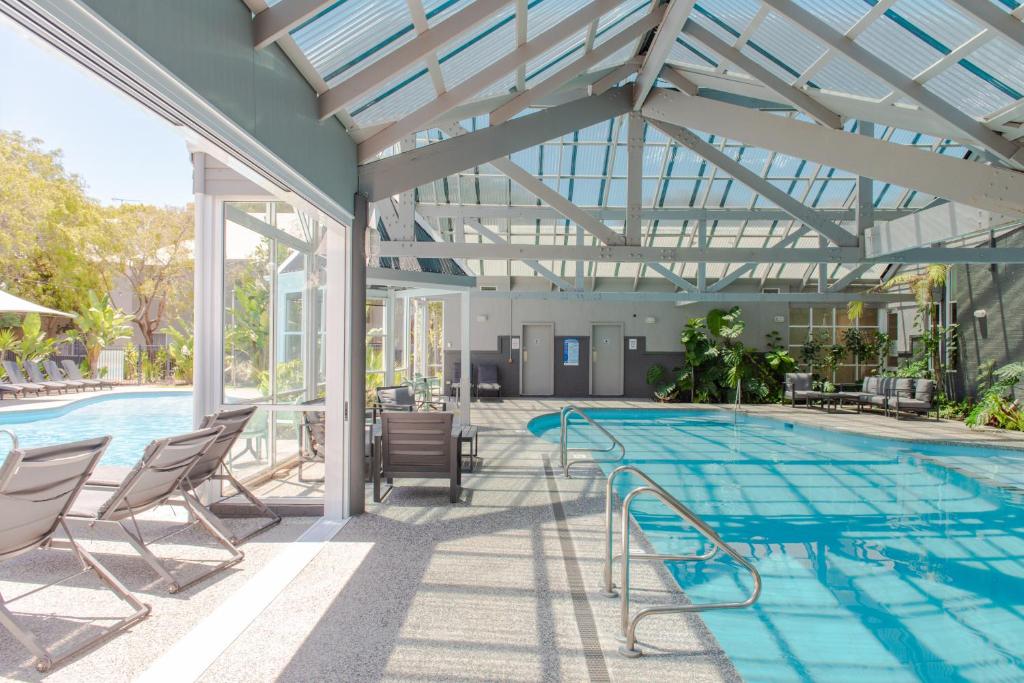 巴瑟尔顿Broadwater Resort WA Tourism Awards 2022 Gold Winner的一个带椅子和玻璃天花板的游泳池