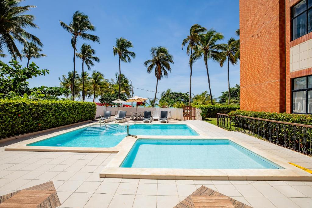 马塞约Moriah Maceió Beach Hotel的一座棕榈树游泳池和一座建筑