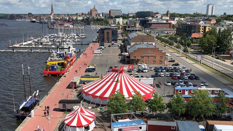 罗斯托克Circus Fantasia的水边的码头,有红白色的帐篷