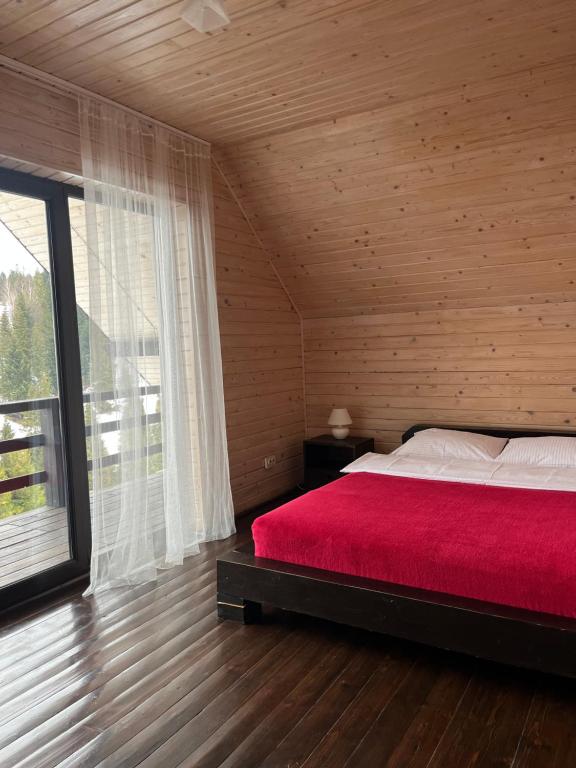 RosokhachCottages Shepit Lisu的一间卧室设有红色的床和大窗户