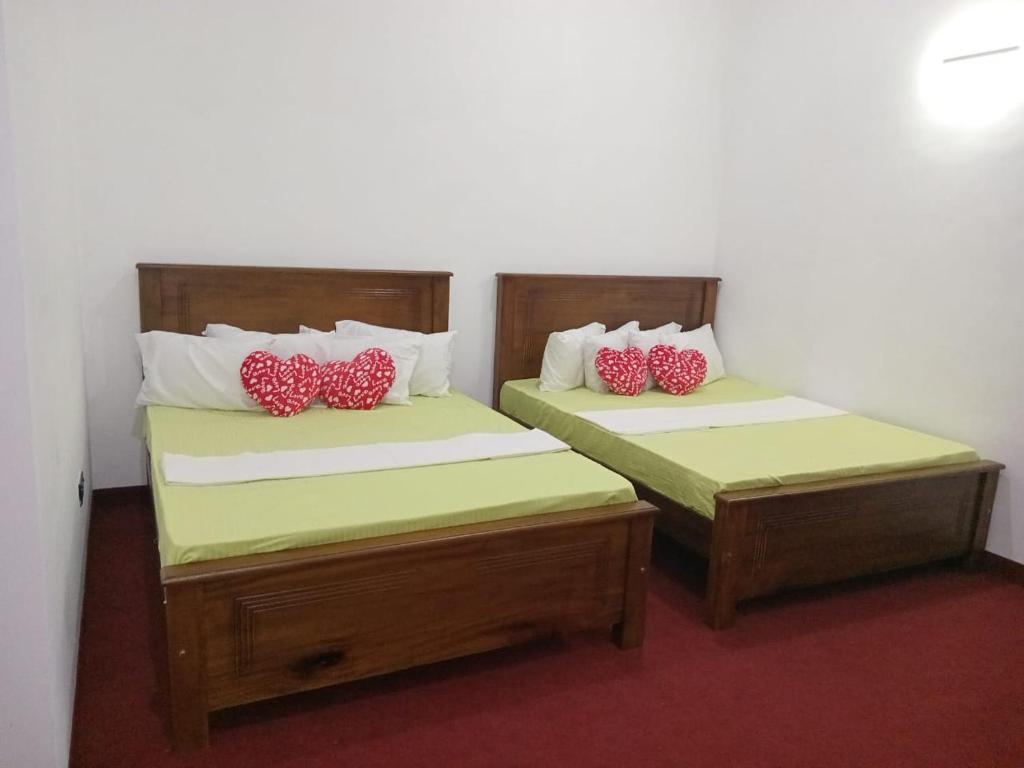 加姆波勒Idom Cozy的客房内的两张床和红色枕头
