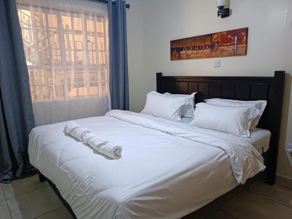 内罗毕Lux Suites Neema Court Furnished Apartments的一张配有白色床单和枕头的大床