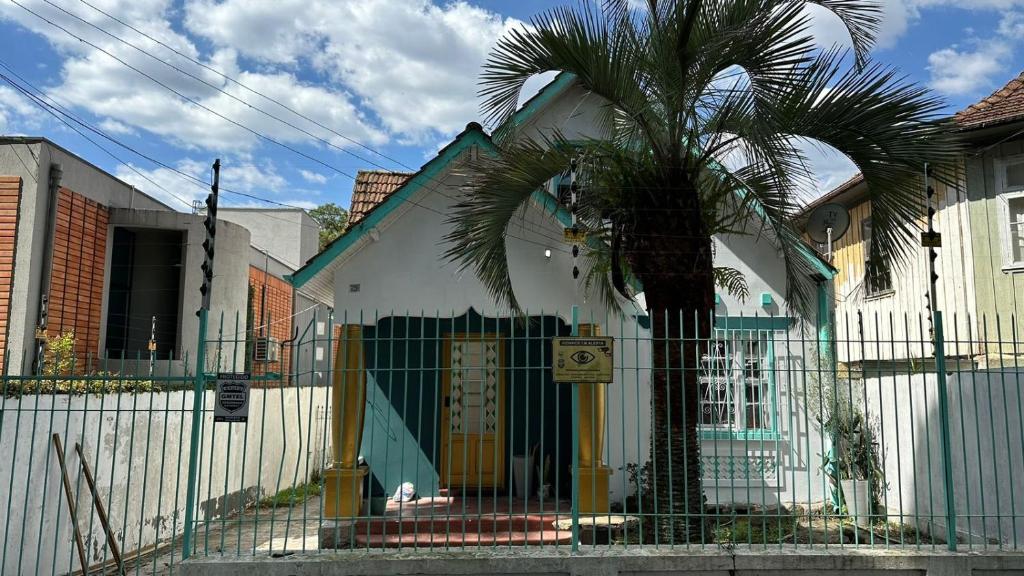 库里提巴Hostel Hug Brasil的围栏前有棕榈树的房子