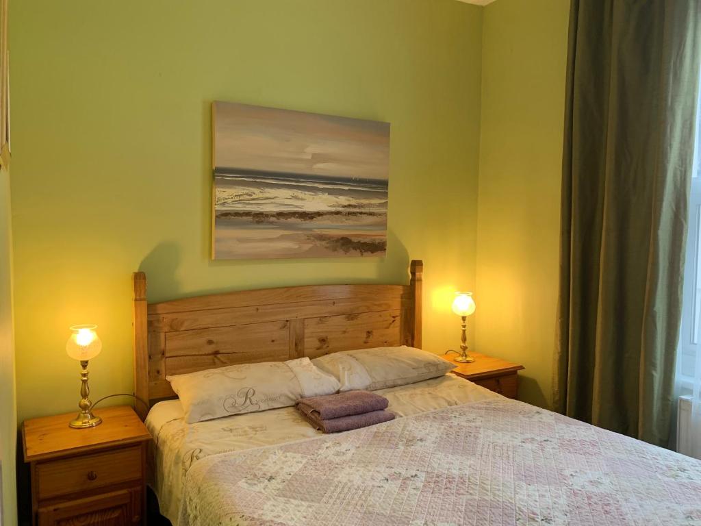 滨海绍森德Apartments near the sea with free parking Southend-on-Sea的一间卧室配有一张带两盏灯和一幅画的床铺