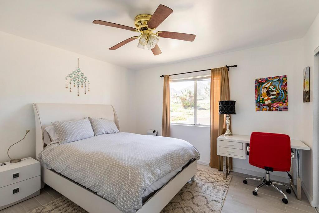约书亚树Electroliquid&#39;s Casa Pueblo Joshua Tree的一间卧室配有一张床、一张桌子和吊扇