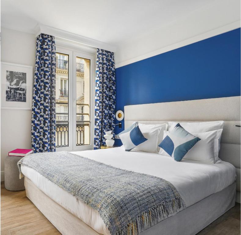 巴黎香榭丽舍歌剧院酒店的一间卧室设有一张蓝色墙壁的大床