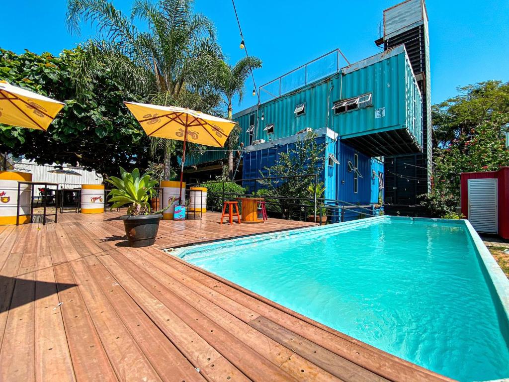 伊瓜苏特里斯集装箱旅舍的木制甲板上的游泳池,配有遮阳伞