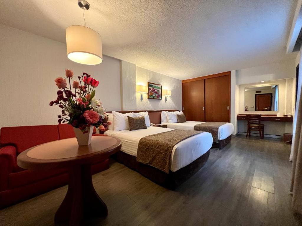 墨西哥城都市酒店的酒店客房,设有两张床和一张鲜花桌。